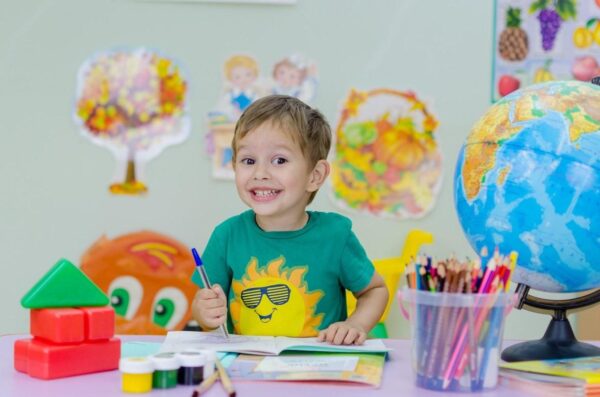 un bambino sorridente a scuola che fa un disegno